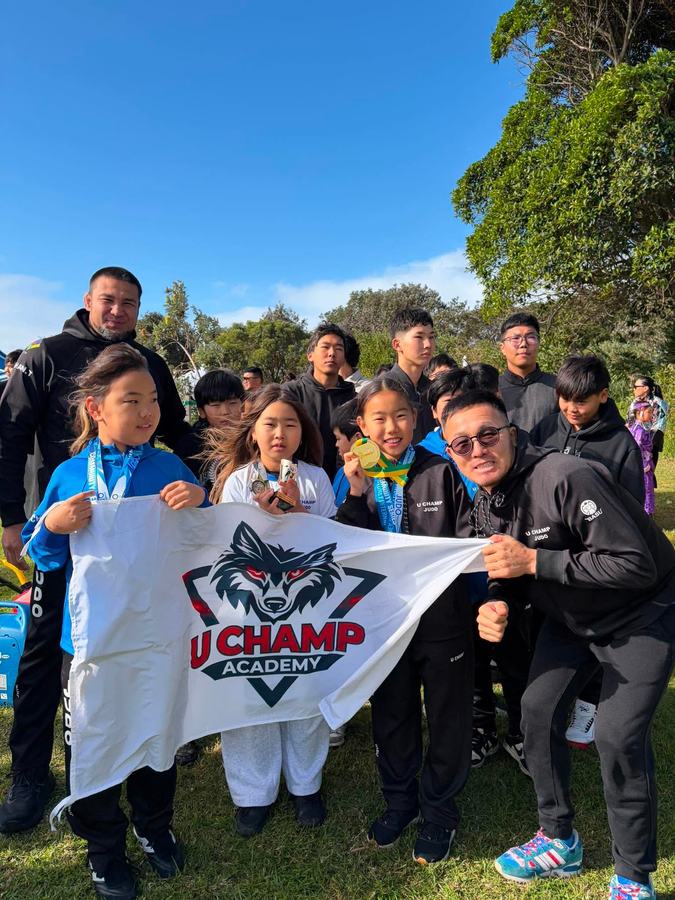 U Champ Academy Judo team holding the club flag